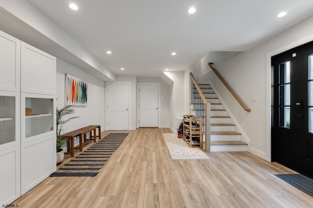 foyer entrance featuring light wood-type flooring, baseboards, recessed lighting, and stairs