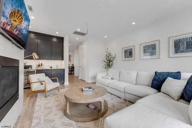 living room with recessed lighting, visible vents, and light wood finished floors