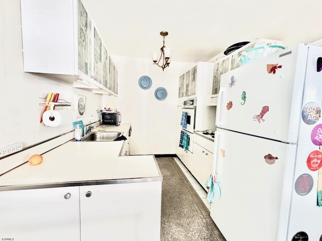 kitchen with white appliances, white cabinetry, light countertops, and a sink