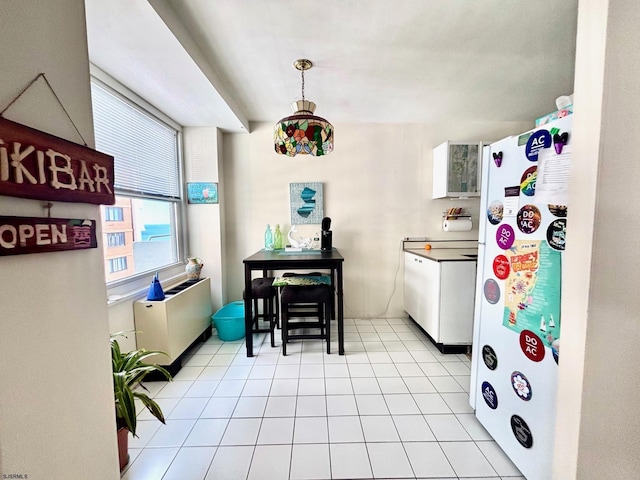 kitchen featuring freestanding refrigerator, hanging light fixtures, and light tile patterned floors