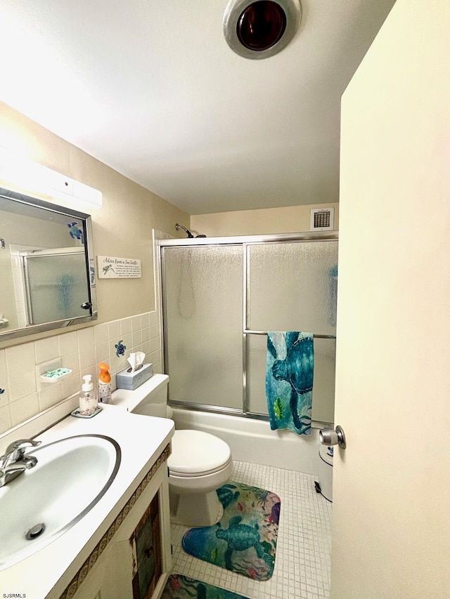 full bathroom with enclosed tub / shower combo, tile patterned flooring, toilet, visible vents, and tile walls