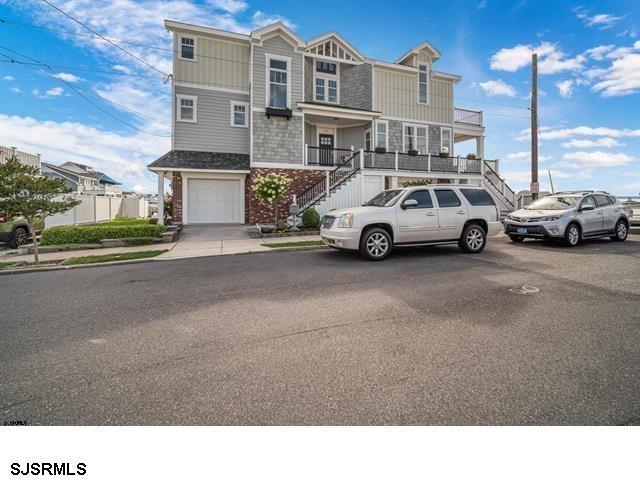 townhome / multi-family property with brick siding, stairway, and an attached garage