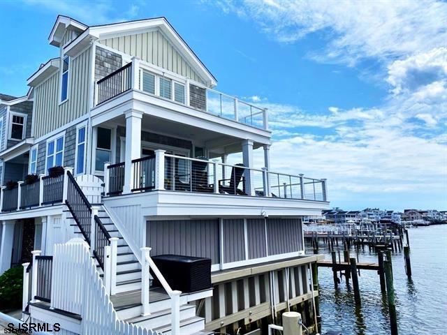 view of side of home featuring central AC, a water view, stairs, a boat dock, and board and batten siding