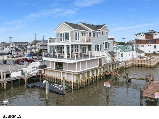 back of property with a water view, a residential view, and a balcony