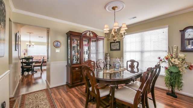 dining room featuring plenty of natural light, wood finished floors, visible vents, and a notable chandelier