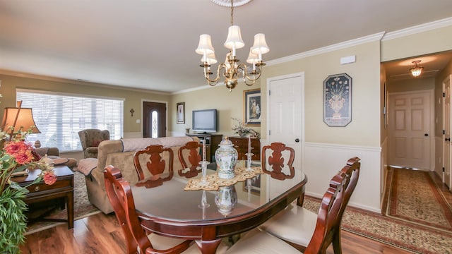 dining room featuring a wainscoted wall, crown molding, an inviting chandelier, and wood finished floors