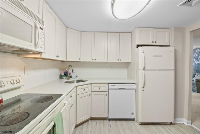 kitchen with white appliances, visible vents, white cabinets, light countertops, and a sink