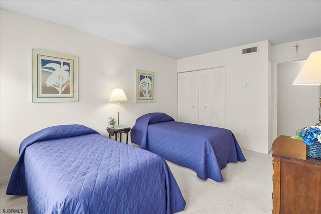 carpeted bedroom featuring visible vents and a closet