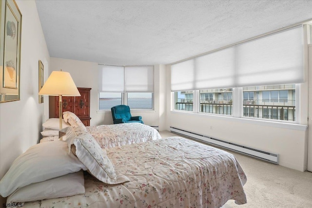 carpeted bedroom featuring a baseboard heating unit and a textured ceiling