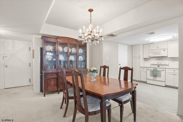 dining area featuring an inviting chandelier, visible vents, and light colored carpet