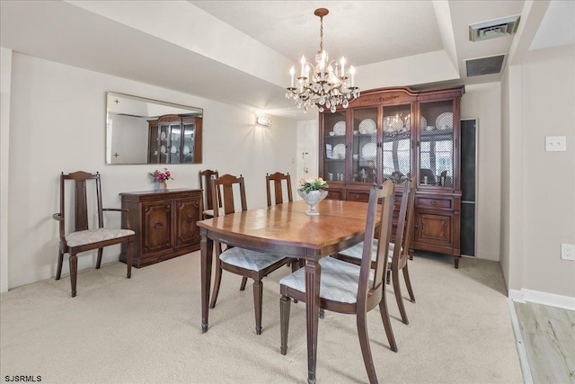 dining space featuring a chandelier, a tray ceiling, and visible vents