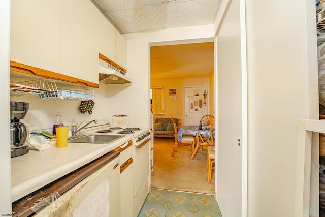 kitchen with light countertops, white cabinets, a sink, and under cabinet range hood