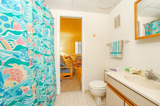 bathroom with visible vents, toilet, vanity, tile patterned flooring, and a drop ceiling