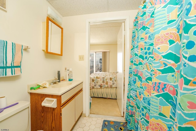 full bath with connected bathroom, vanity, toilet, and a textured ceiling