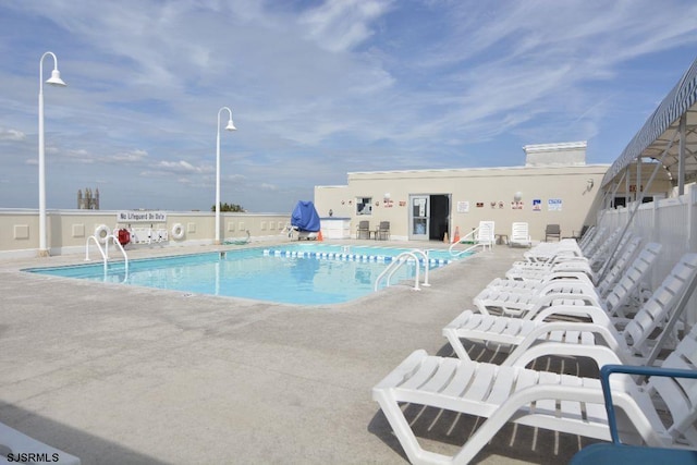 pool with a patio and fence