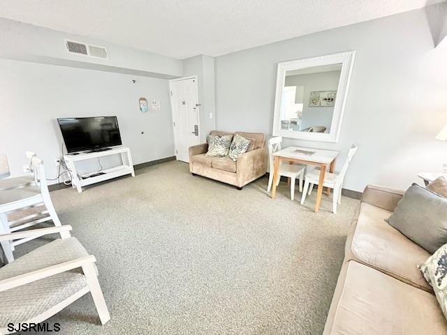 carpeted living area featuring baseboards, visible vents, and a textured ceiling