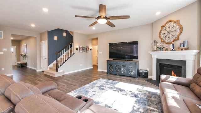 living room with a glass covered fireplace, wood finished floors, recessed lighting, and stairs