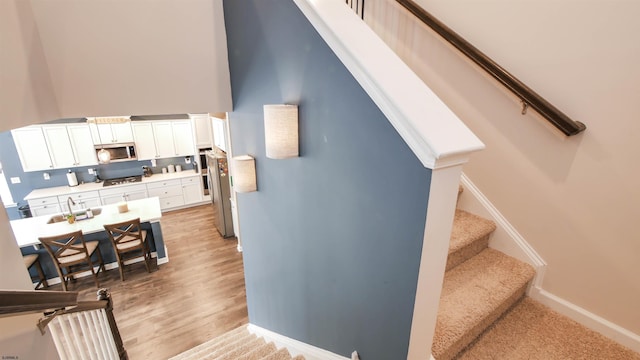 stairs with a high ceiling, baseboards, and wood finished floors