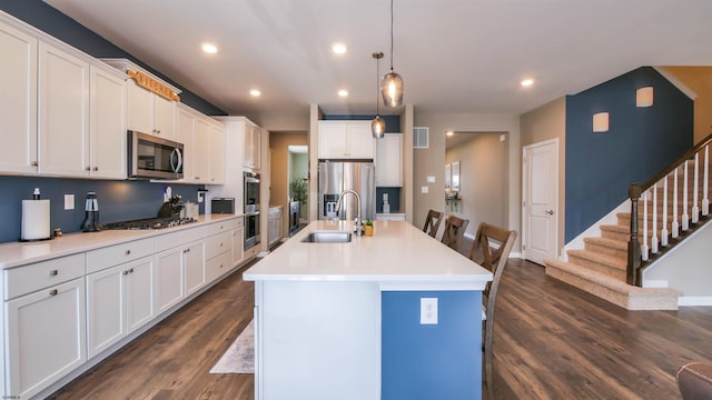 kitchen with appliances with stainless steel finishes, dark wood finished floors, white cabinetry, and a sink