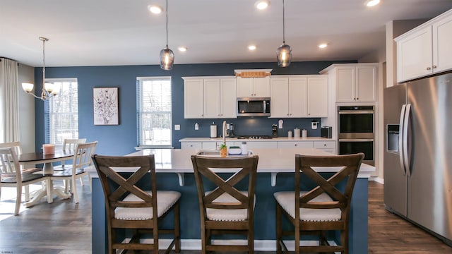 kitchen featuring stainless steel appliances, a kitchen island with sink, light countertops, and backsplash