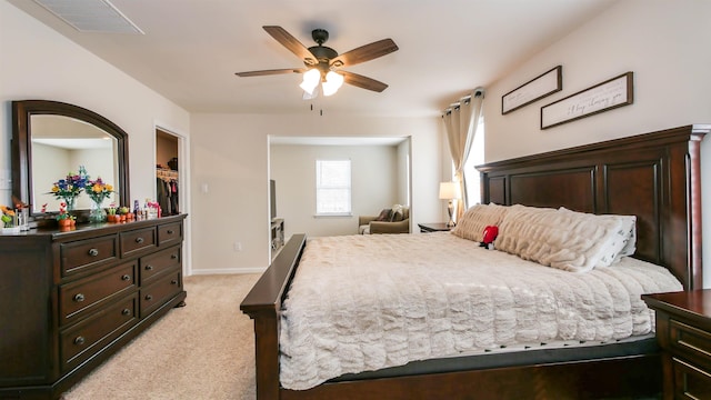 bedroom featuring baseboards, visible vents, light colored carpet, ceiling fan, and a spacious closet