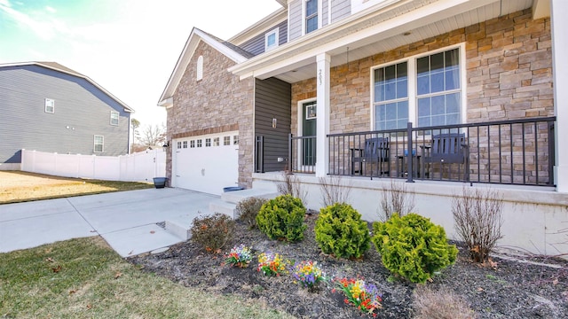 view of front of house with a porch, stone siding, fence, and driveway