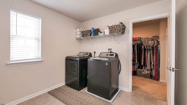 clothes washing area with light tile patterned floors, laundry area, independent washer and dryer, and baseboards