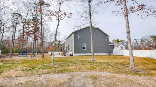 view of side of property with a yard, a trampoline, and fence