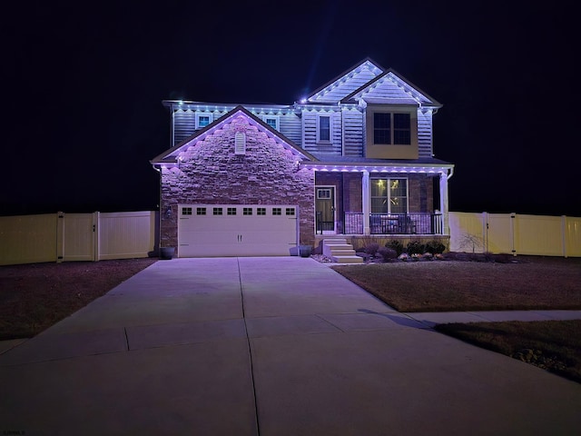 view of front of property featuring a porch, a garage, concrete driveway, stone siding, and a gate