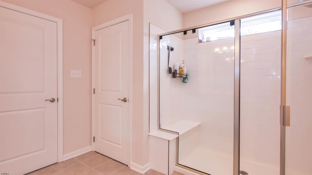 bathroom with baseboards, a shower stall, and tile patterned floors