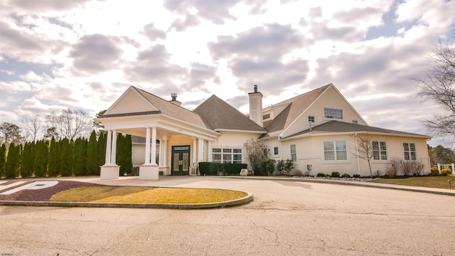 view of front of house with stucco siding, a chimney, and french doors