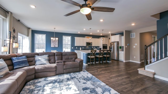 living area with dark wood-style floors, a wealth of natural light, stairway, and recessed lighting