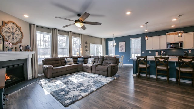 living area with recessed lighting, dark wood finished floors, a wealth of natural light, and a glass covered fireplace