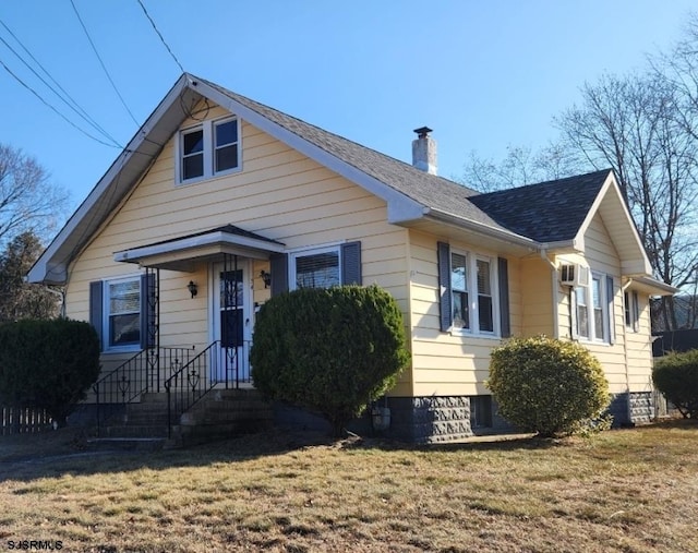 bungalow-style house featuring roof with shingles, a chimney, and a front yard