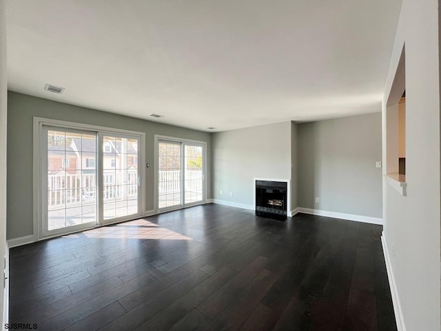 unfurnished living room with baseboards, a fireplace, visible vents, and dark wood-type flooring