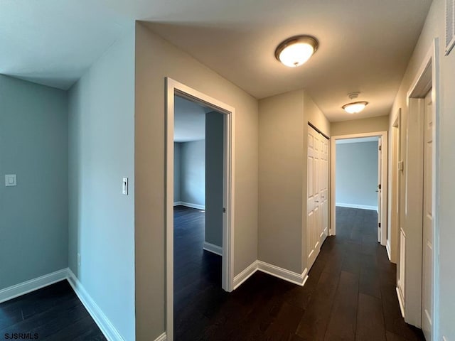 hallway with dark wood-type flooring and baseboards