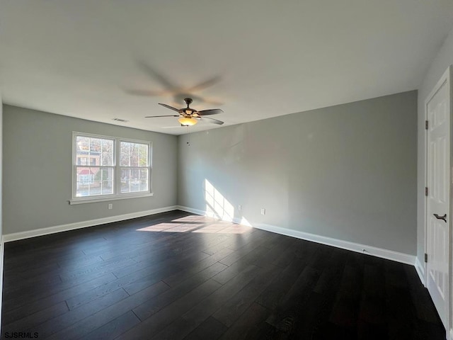 spare room featuring dark wood-style floors, ceiling fan, visible vents, and baseboards