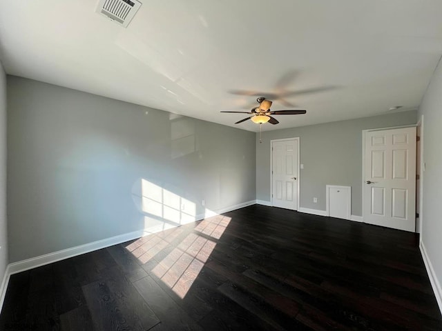 spare room featuring a ceiling fan, baseboards, visible vents, and dark wood-type flooring