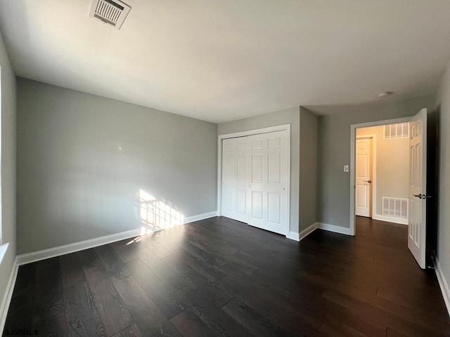 unfurnished bedroom featuring dark wood-style flooring, visible vents, and baseboards