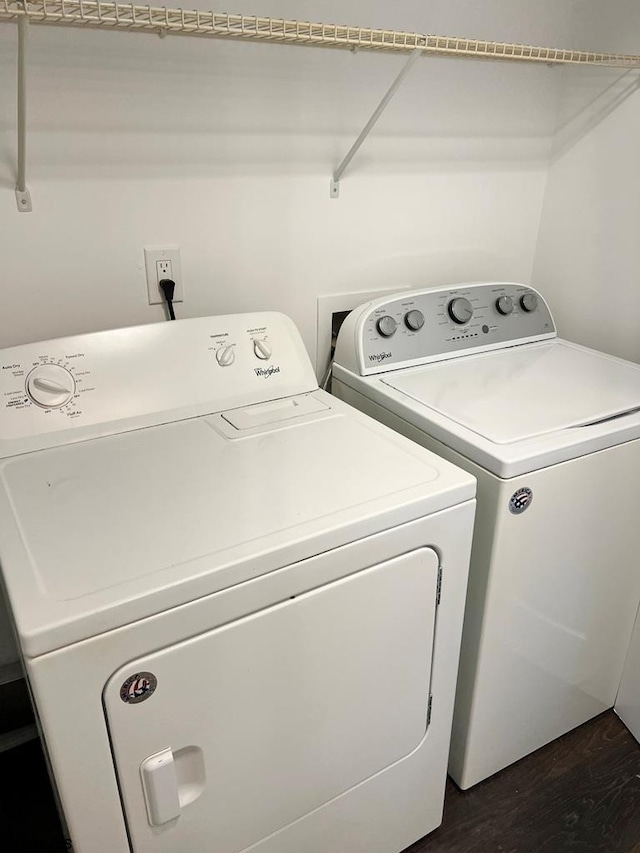 clothes washing area with laundry area, separate washer and dryer, and dark wood finished floors