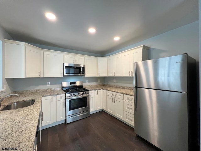 kitchen featuring recessed lighting, stainless steel appliances, dark wood-type flooring, a sink, and light stone countertops