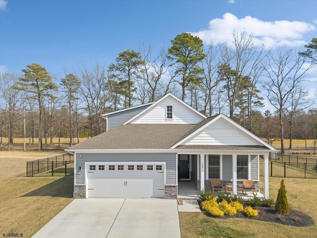 view of front of home with covered porch, concrete driveway, a garage, stone siding, and a front lawn