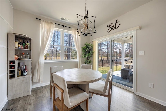 dining area with a notable chandelier, dark wood-style flooring, visible vents, and baseboards