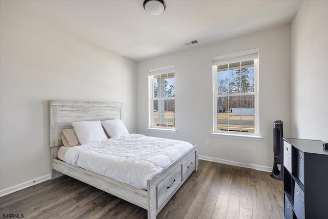 bedroom featuring baseboards, visible vents, and wood finished floors