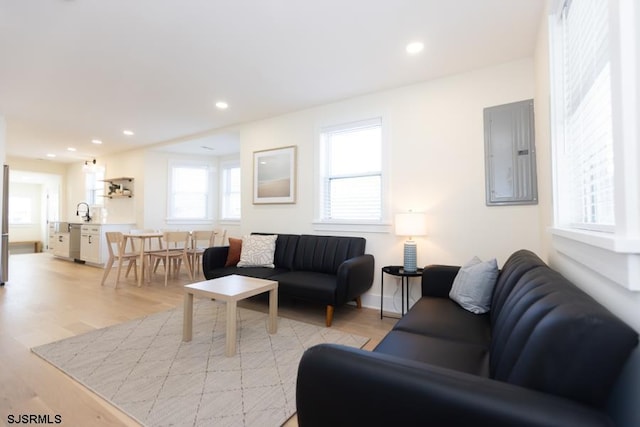 living room with light wood-type flooring, electric panel, baseboards, and recessed lighting