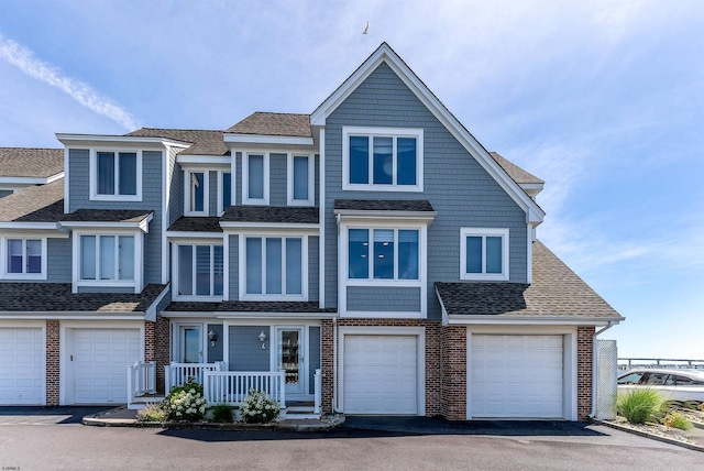 view of front of home with a shingled roof, brick siding, driveway, and an attached garage