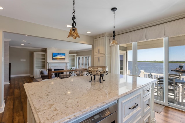 kitchen with light stone counters, a water view, wood finished floors, a fireplace, and ornamental molding