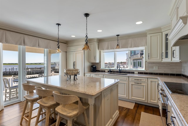 kitchen with black electric stovetop, light stone countertops, a sink, decorative backsplash, and custom range hood