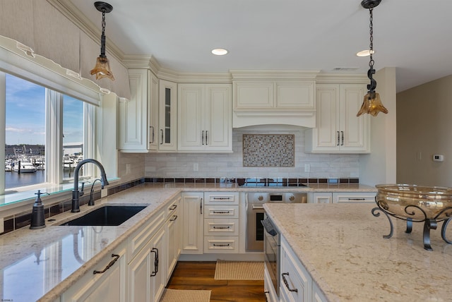 kitchen with a sink, backsplash, black electric stovetop, and light stone countertops