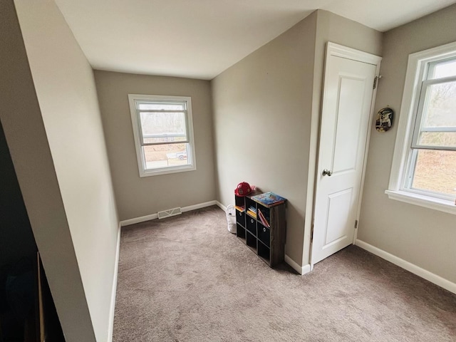 carpeted empty room with baseboards, visible vents, and a healthy amount of sunlight